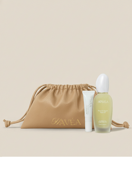 Hair and lip care products including a bottle and tube with a tan drawstring bag on a beige background.