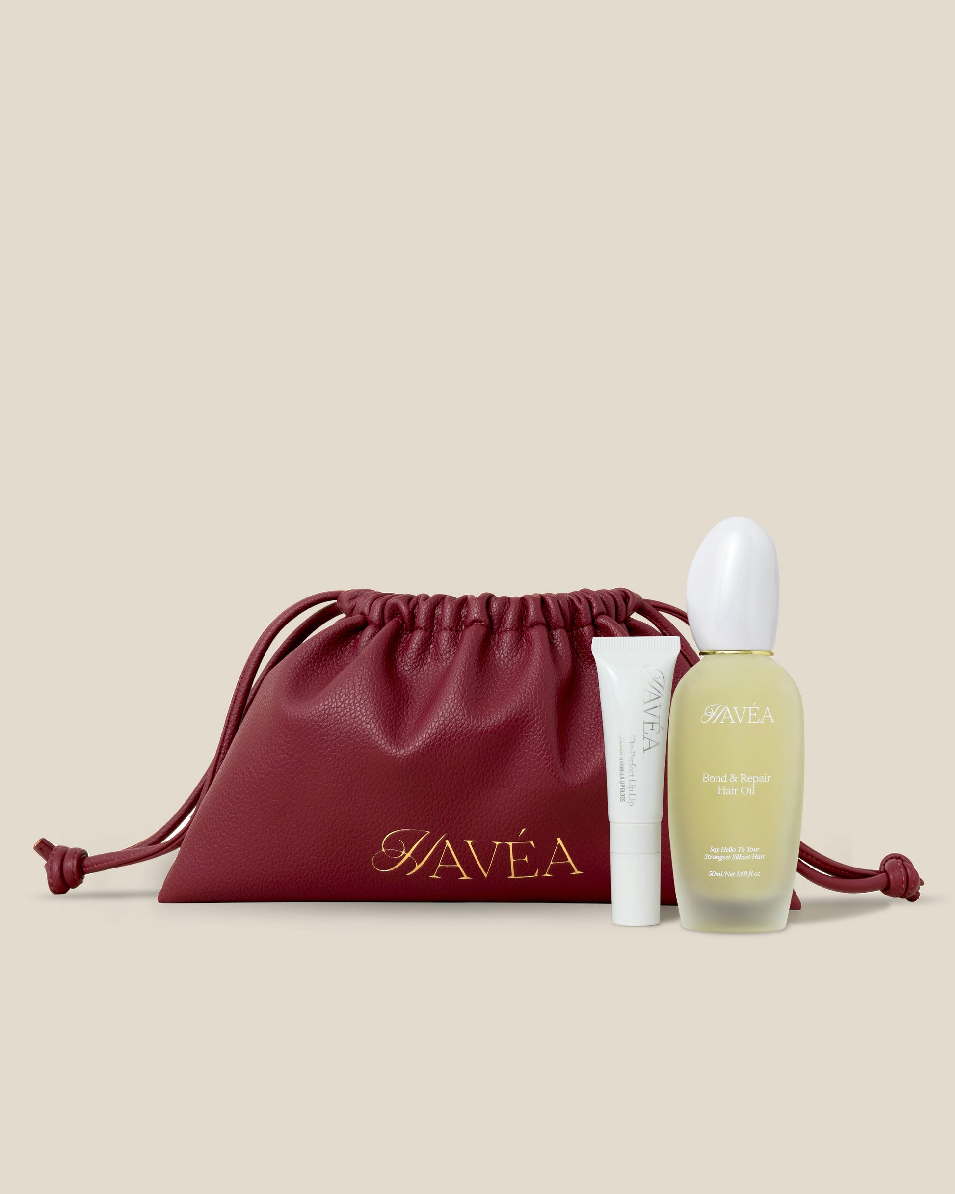 Hair and lip care products including a bottle and tube with a red drawstring bag on a beige background.